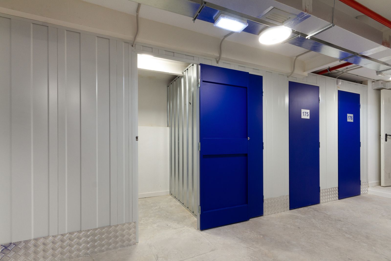 Pasillo de Vaiia Trasteros con puertas azules y un trastero abierto